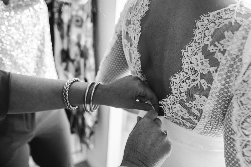 Détail du dos nu en dentelle de la robe de mariée pendant ses préparatifs