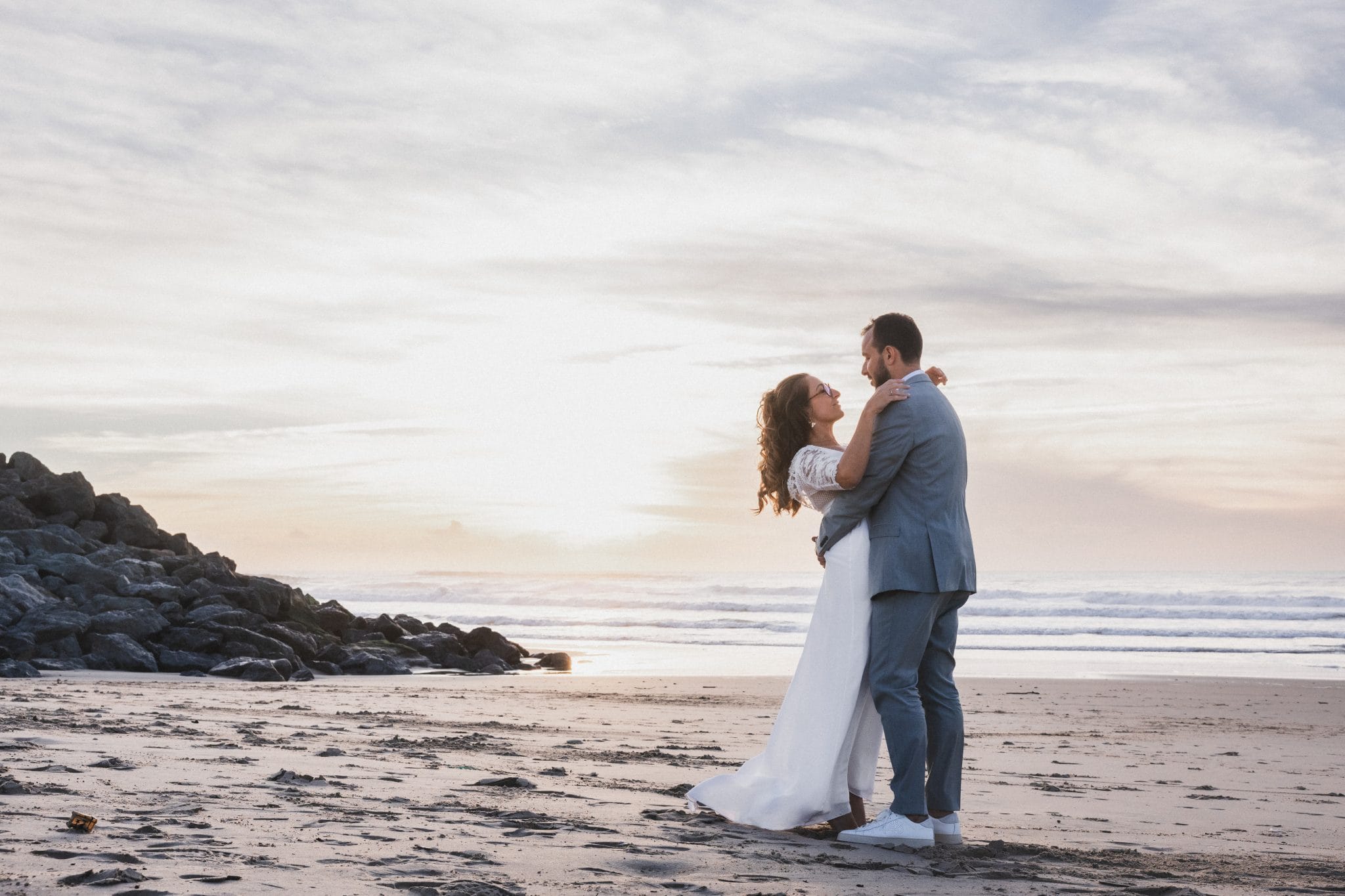 Les mariés se tiennent l'un contre l'autre dans le soleil couchant, durant leur mariage au Pays Basque