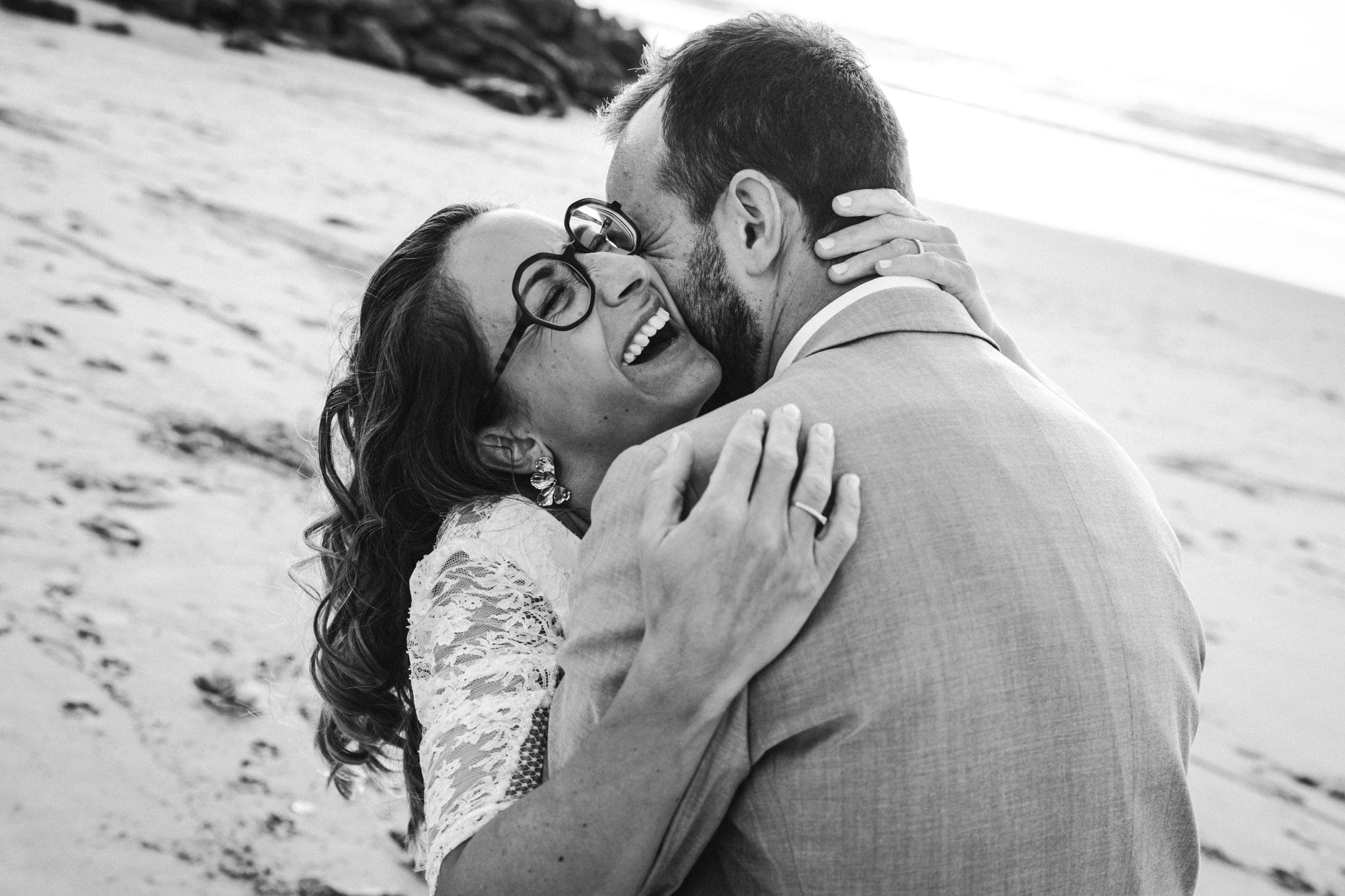 Le marié embrasse sa femme dans le cou, sur la plage, durant son mariage au Pays Basque