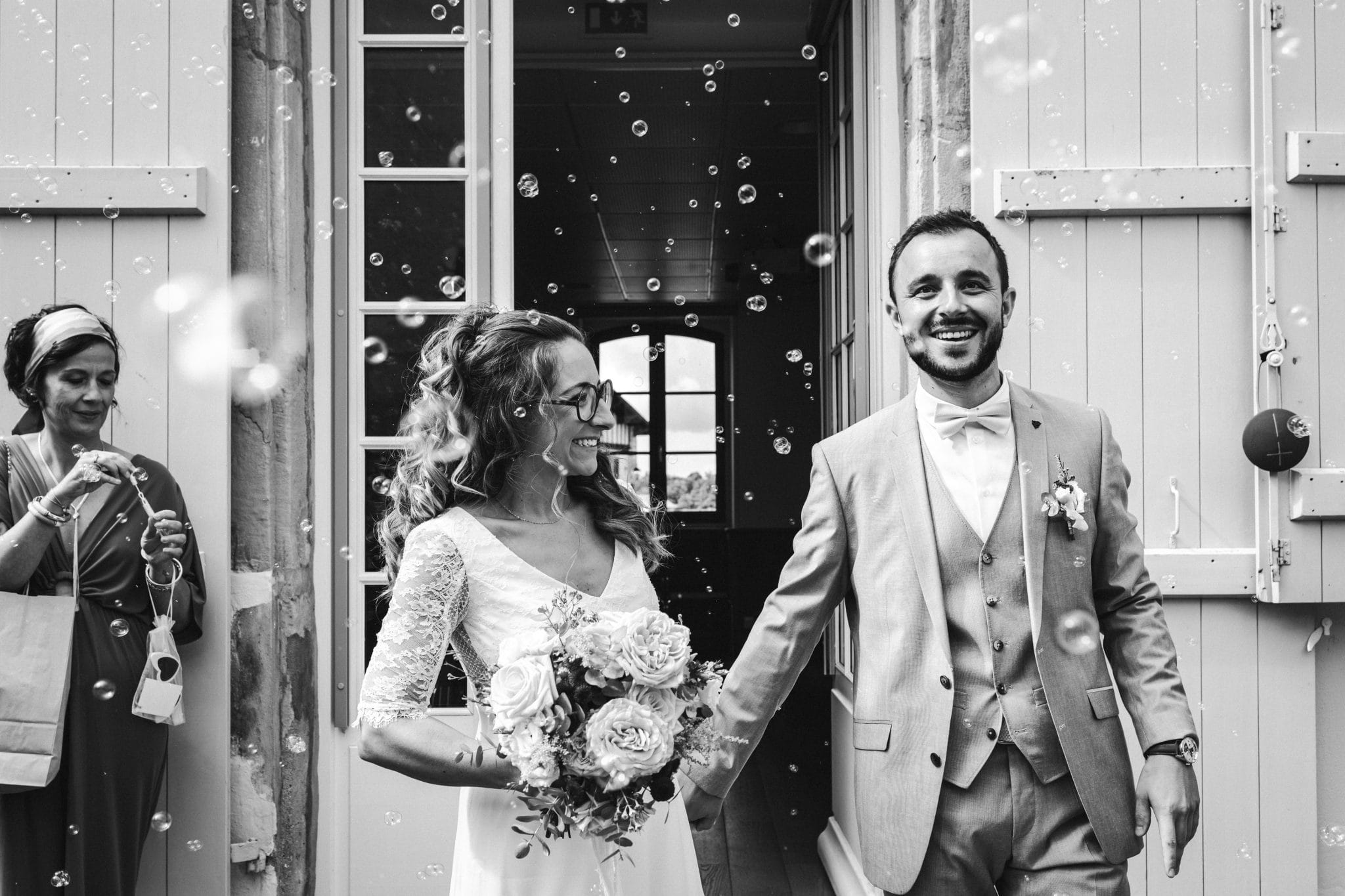 Les mariés sortent de la mairie sous les bulles et les applaudissements de leurs convives durant leur mariage au Pays Basque