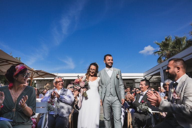Les mariés s'avancent main dans la main dans l'allée qui les mènera à leur cérémonie laïque, lors de leur mariage au Pays Basque