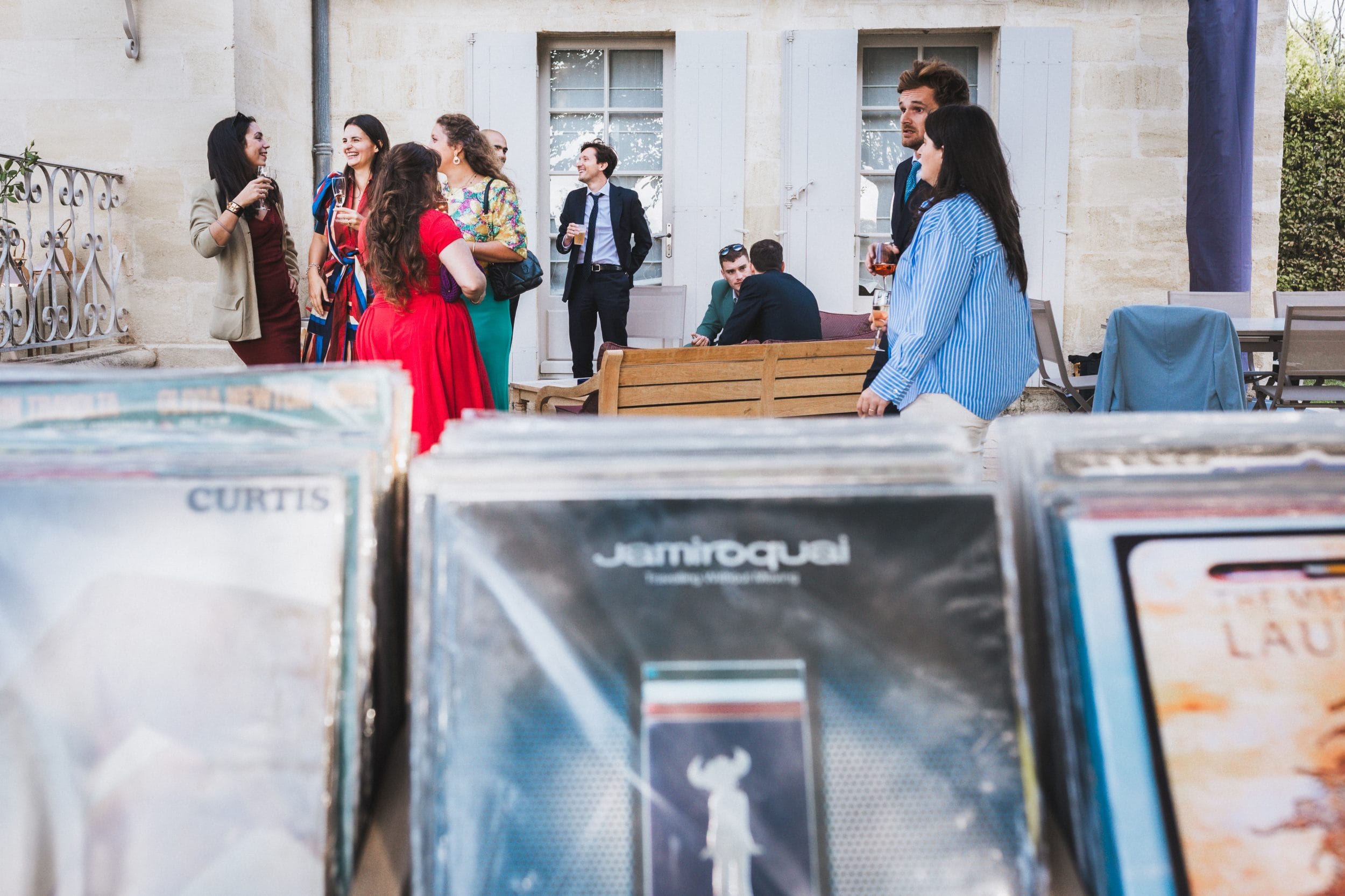 Les vinyles du bar sont au premier plan, les invités discutent au second plan