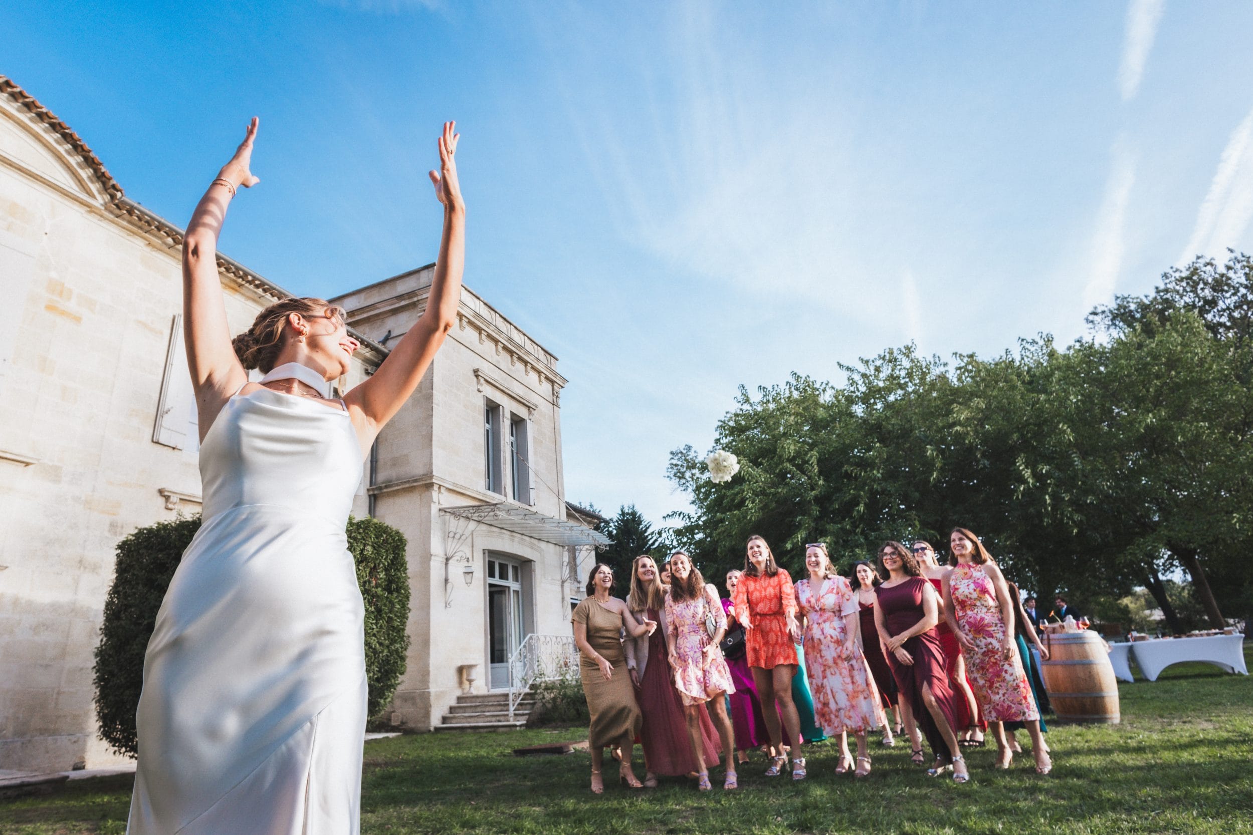 La mariée lance son bouquet à son groupe d'amies durant le cocktail de mariage à Saint-Emilien