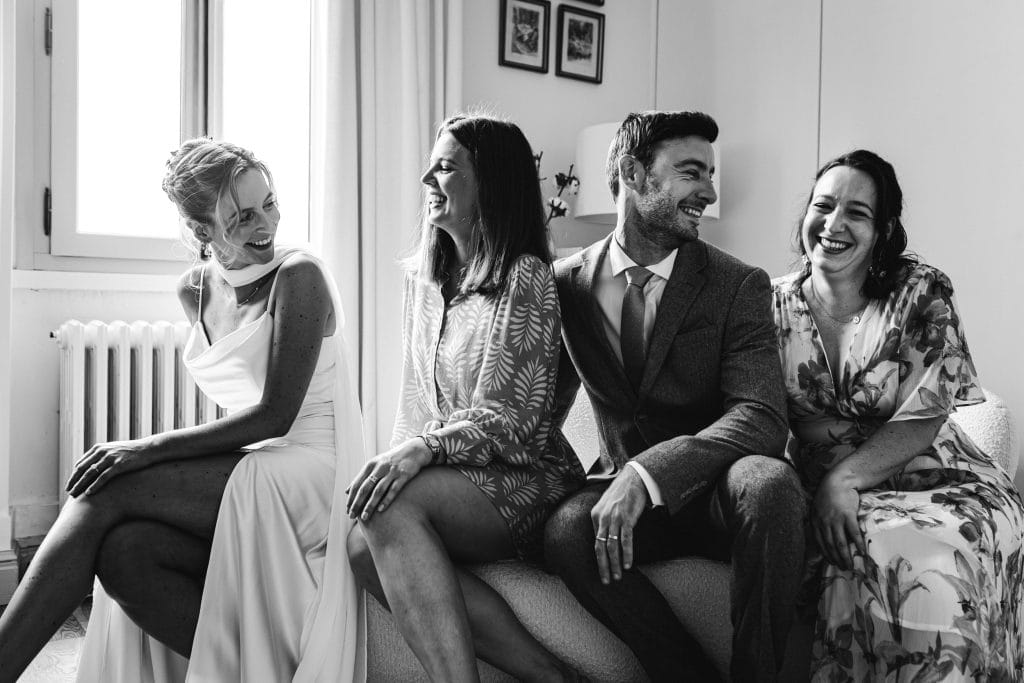 La mariée et ses témoins prennent la pose assis sur une banquette durant ses préparatifs de mariage à Saint-Emilion