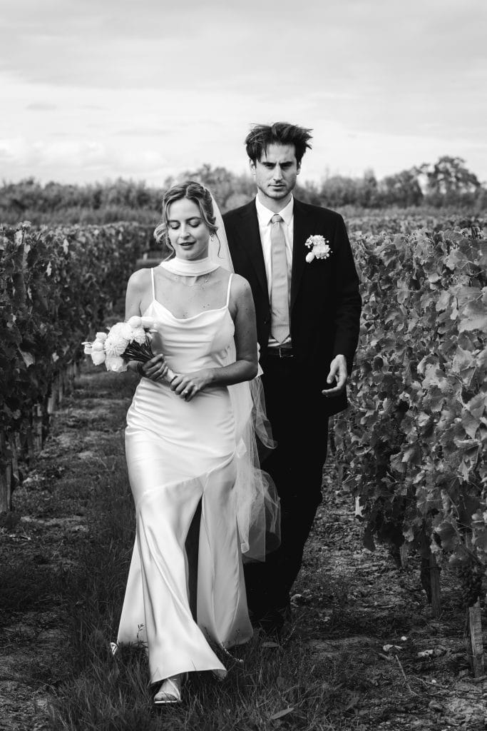Les mariés marchent tranquillement au milieu des vignes lors de leur mariage à Saint-Emilion