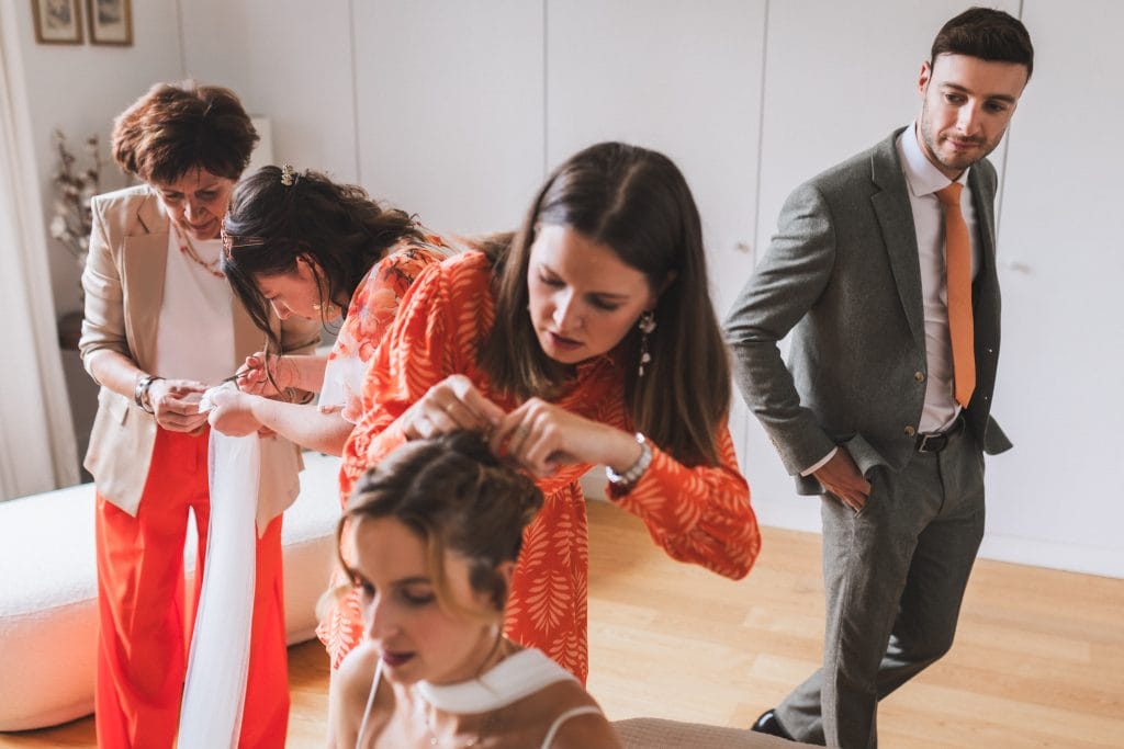 Les témoins et la mère de la mariée s'activent autour de cette dernière afin de lui attacher son voile