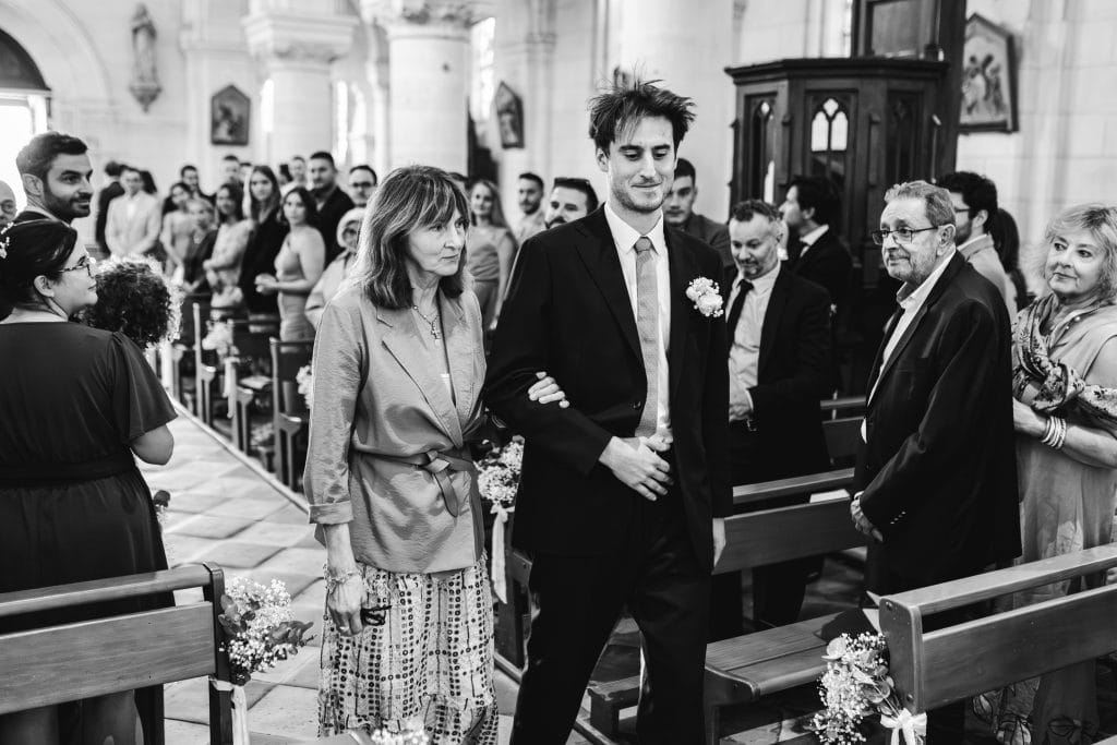 Le marié rentre au bras de sa mère dans l'église de Pomerol pour son mariage à Saint-Emilion