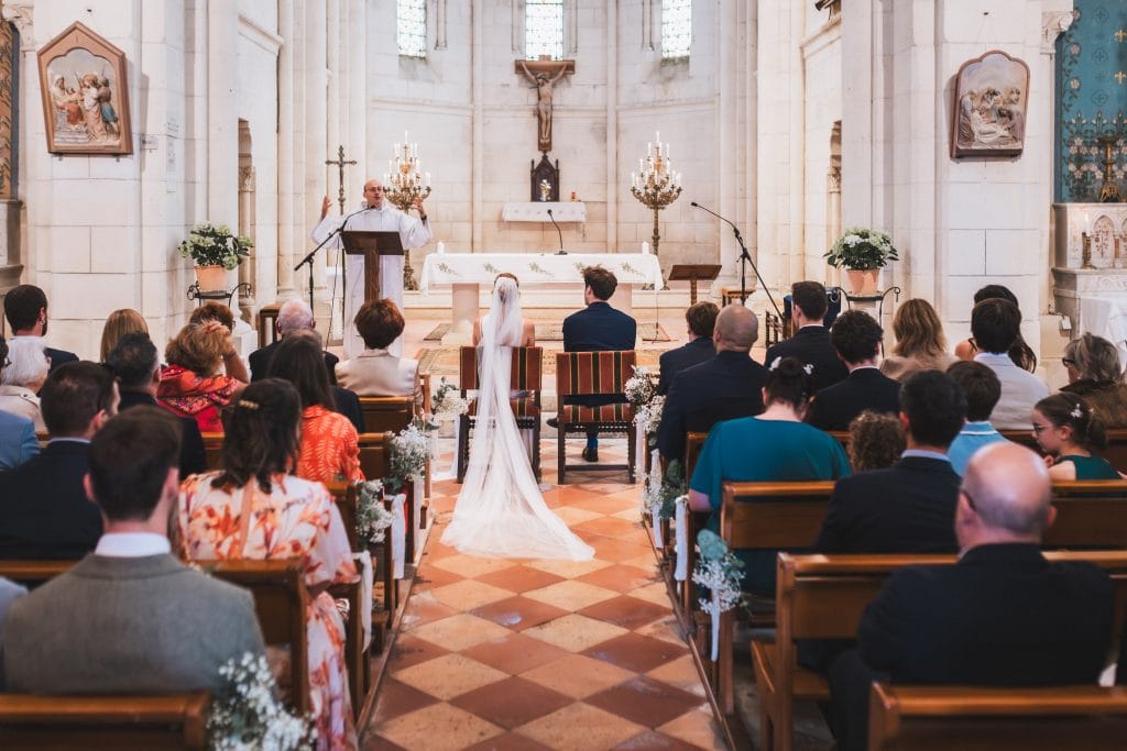 Les mariés, assis dans leurs chaises, écoutent attentivement la bénédiction de mariage du prêtre