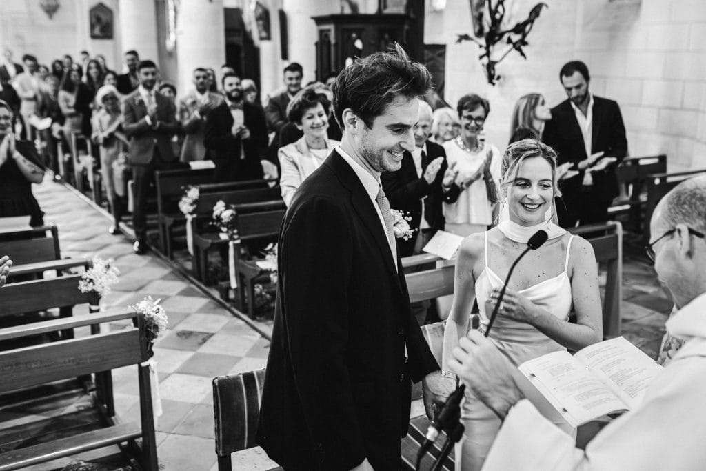 Les mariés sourient au prêtre tandis qu'ils échangent leurs consentements