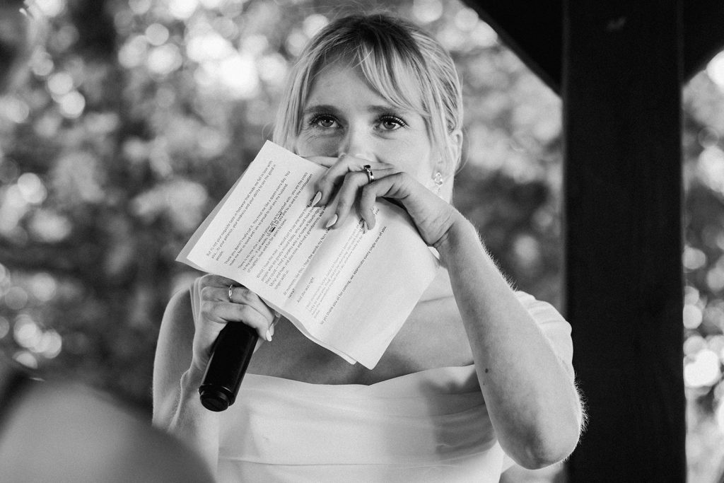 La mariée est très émue pendant qu'elle fait son discours et se cache le visage avec sa main et son papier