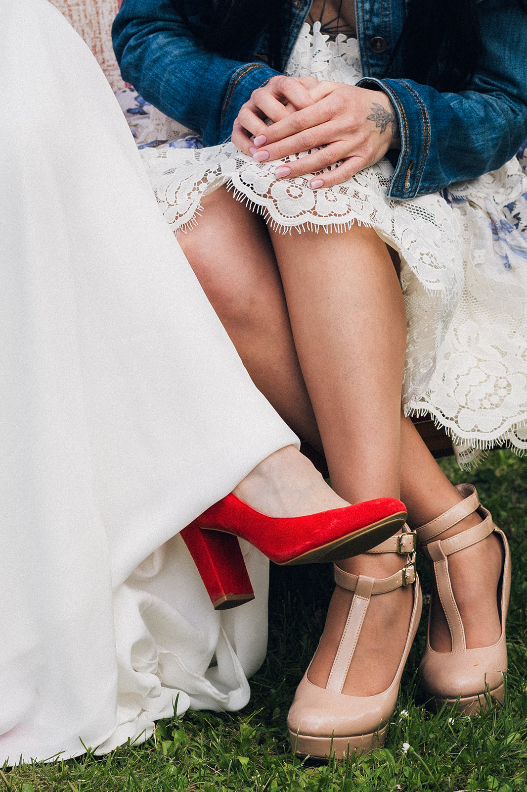 Détail des chaussures de la mariée et d'une invitée, assises sur une banquette pendant les photos de groupe