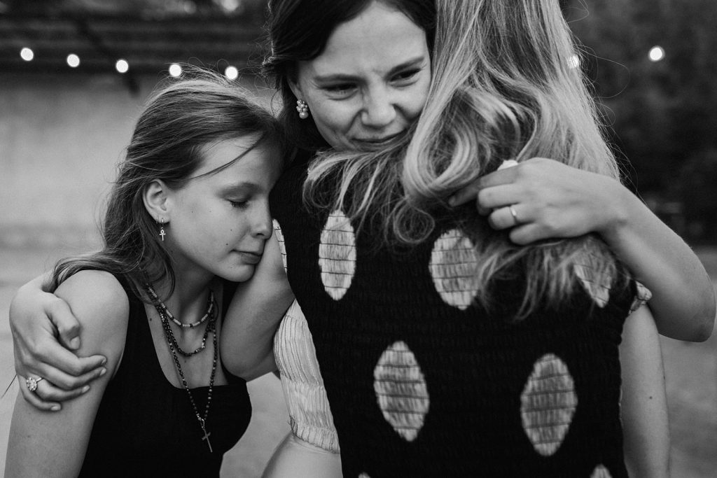 La mariée serre avec émotion ses deux soeurs dans ses bras