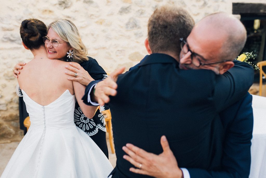 Double câlin entre les mariés et les parents de la mariée après leur discours